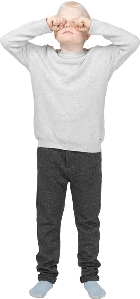 Front view of a boy rubbing his eyes with fists