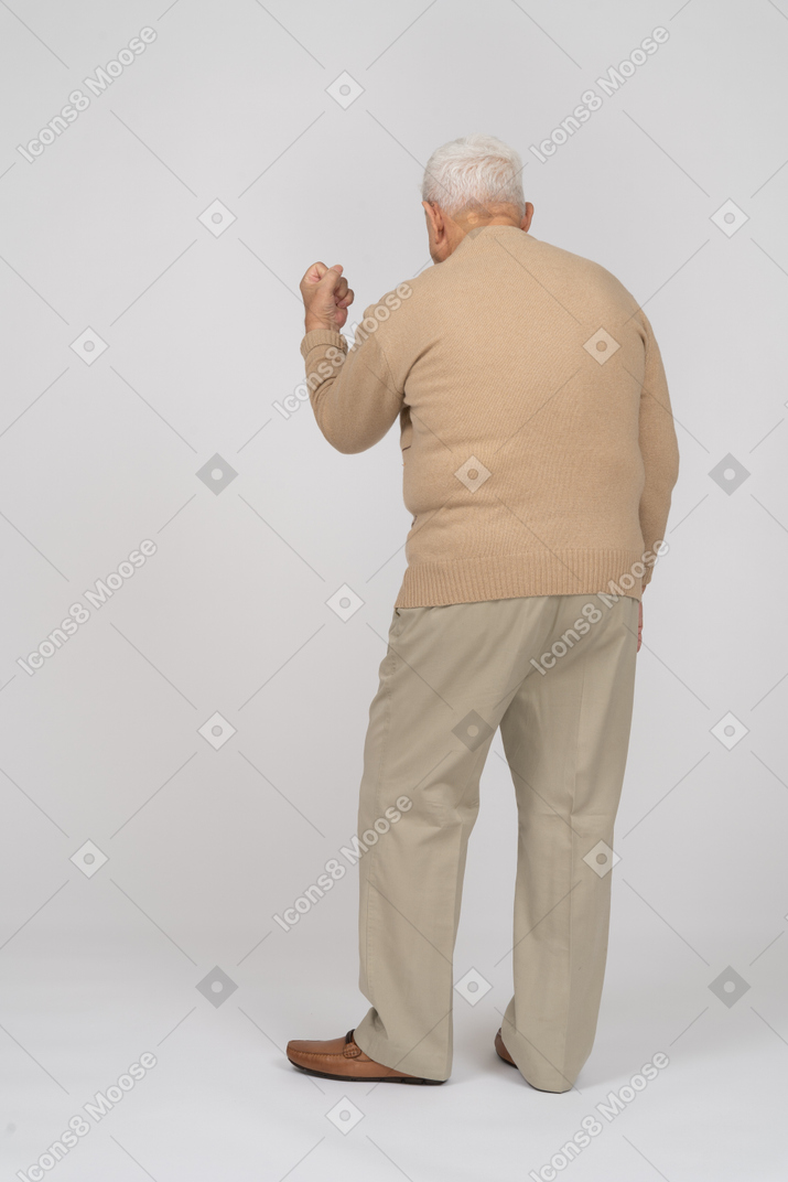 Rear view of an old man in casual clothes showing fist