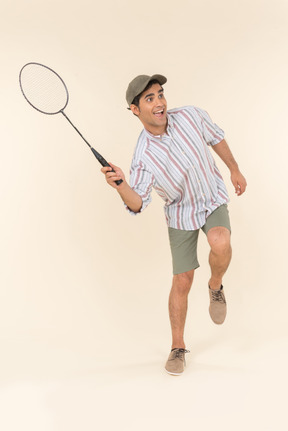 Aufgeregt aussehender junger kaukasischer mann, der tennisschläger hält