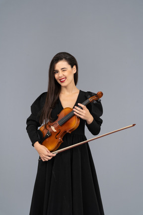 Close-up of a cheerful young lady in black dress holding the violin