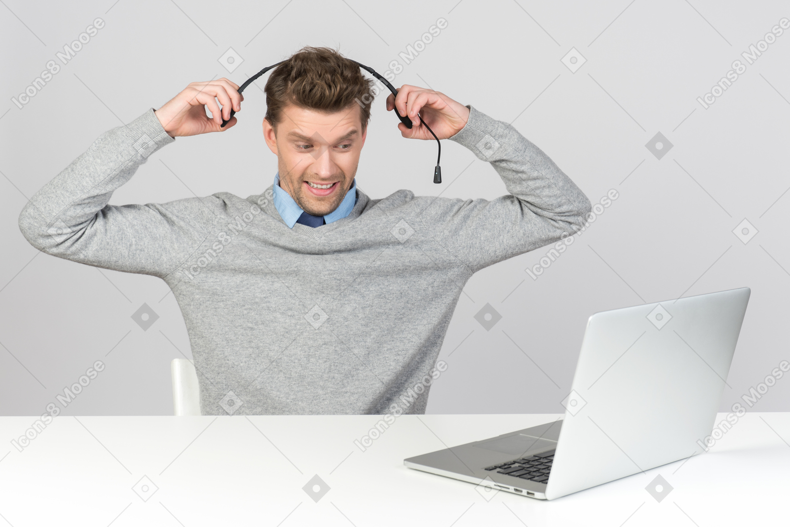 Call center agent pulling off his headset while working on computer