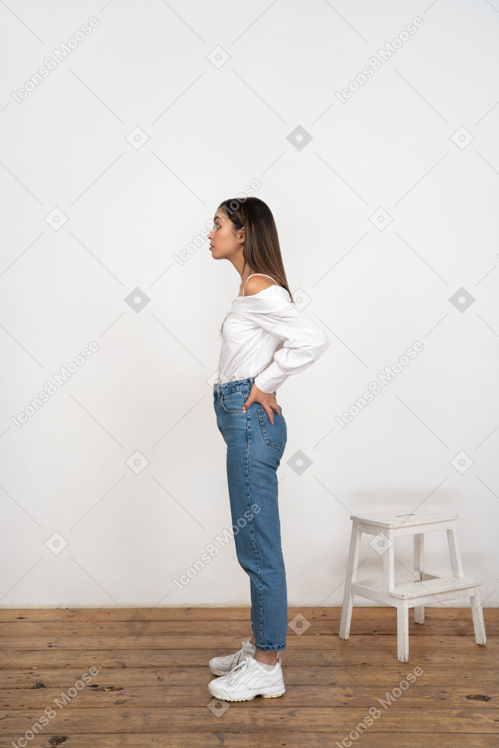 Profile of young woman standing with hands on lower back