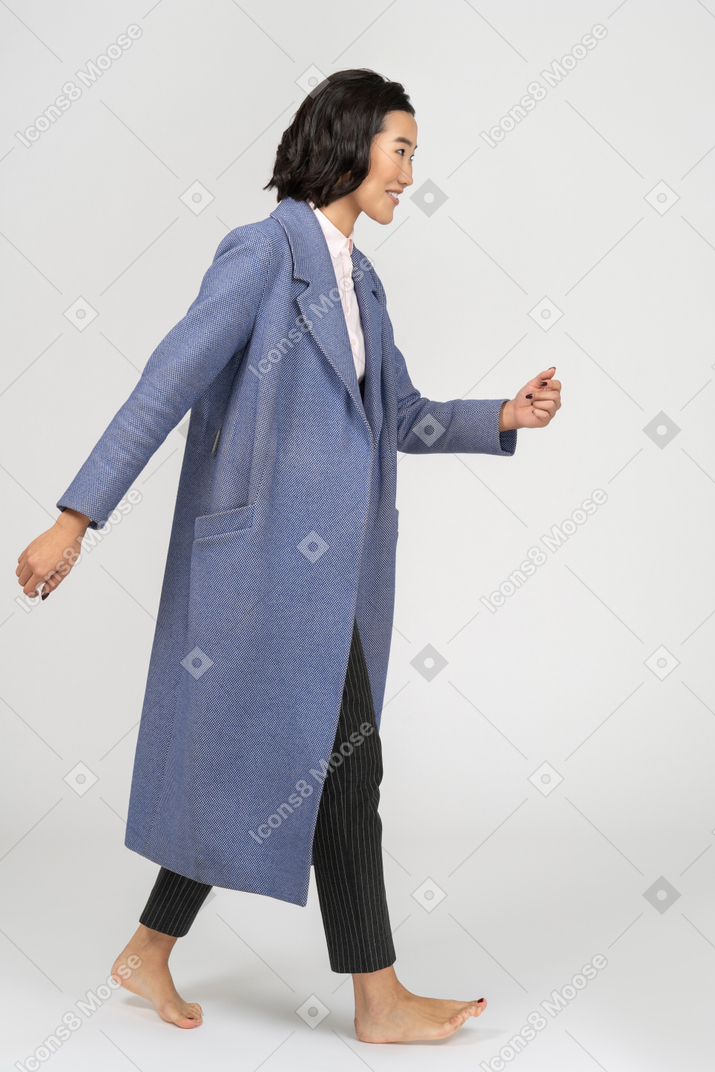 맨발로 걷는 코트를 입은 젊은 여성
