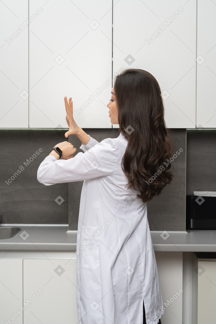 Woman in lab coat using her smartwatch