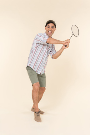 Excited looking young caucasian guy holding tennis racket