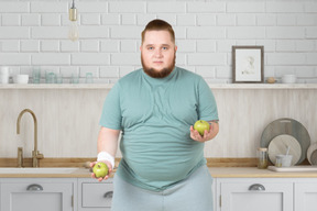 A fat man holding two apples in his hands