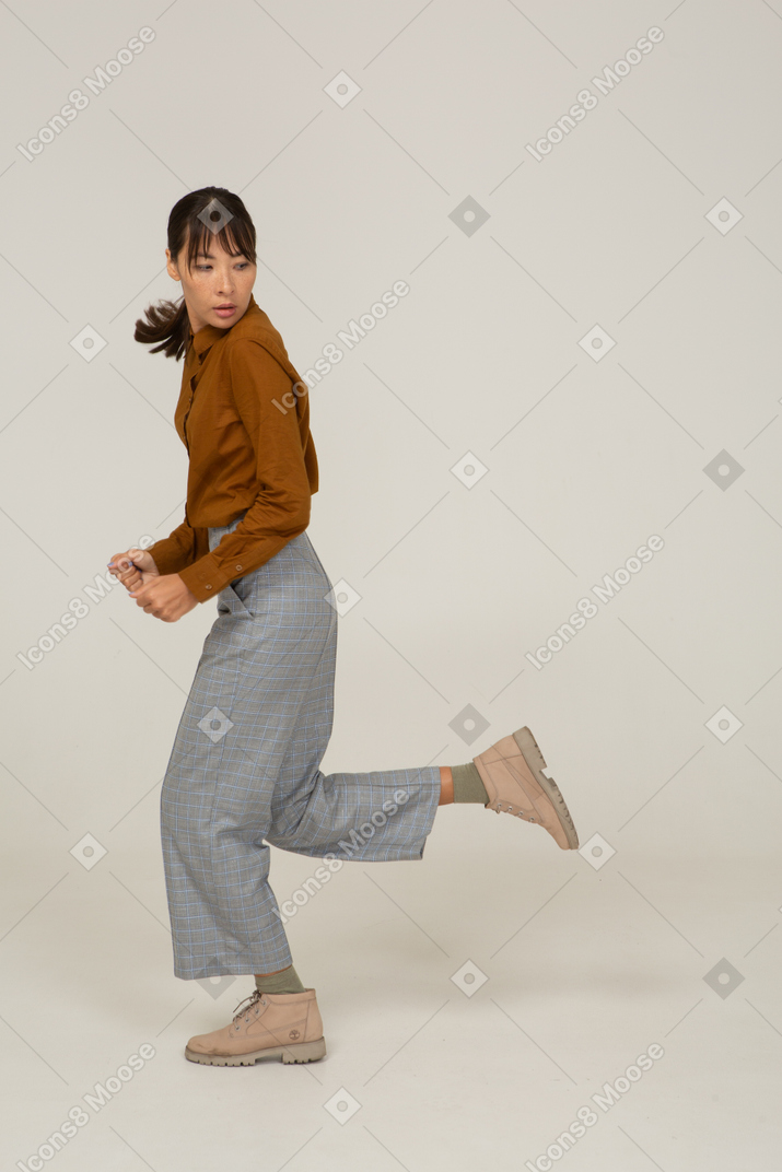 Side view of a running young asian female in breeches and blouse turning away