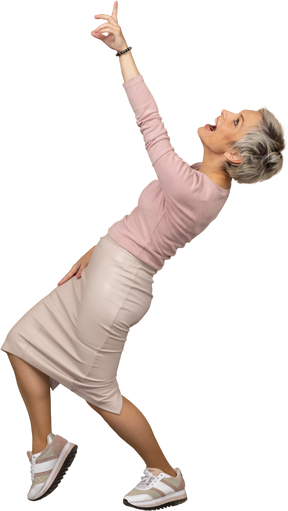 Vista lateral de uma mulher feliz em roupas casuais apontando para cima com o dedo