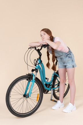 Dreamy teenage girl lying on blue bicycle