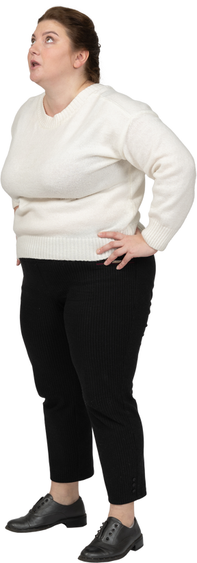 Vista lateral de uma mulher gorda em roupas casuais em pé com as mãos na cintura