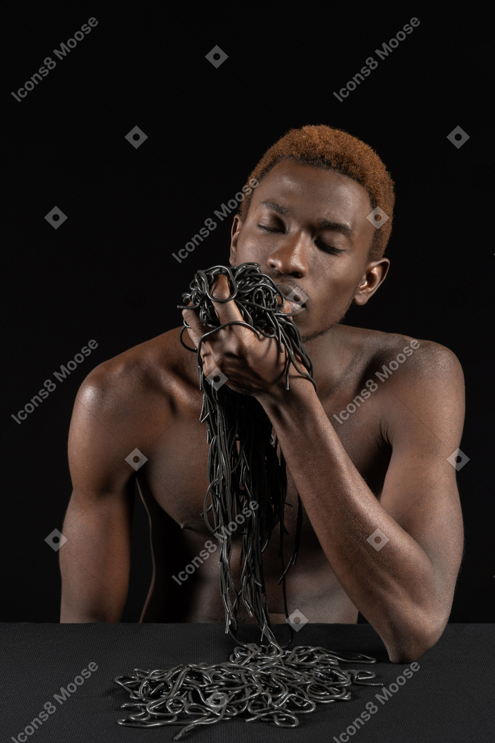腕一杯のパスタを持った若いアフロ男の正面図