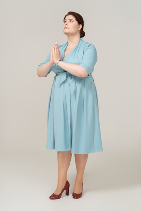 Vista frontal de uma mulher de vestido azul fazendo um gesto de oração