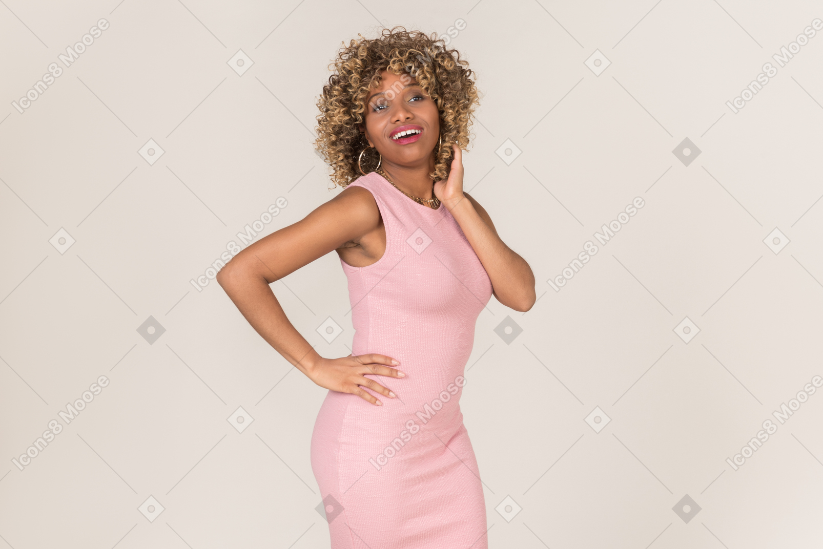 Une femme en robe rose et la main sur sa taille fixant ses cheveux