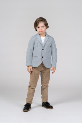 Front view of young boy in blue jacket and brown pants