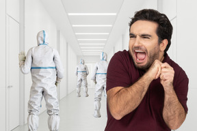Scared man is standing in front of a group of people with protective suits