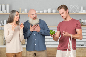 A man taking out a vegetable out of bag next to family looking shocked