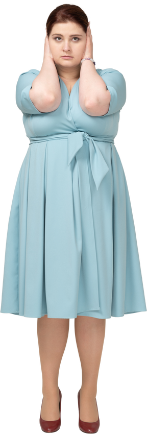 손으로 귀를 덮고 있는 파란 드레스를 입은 여성의 전면 모습