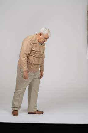 Anciano con ropa informal mirando hacia abajo