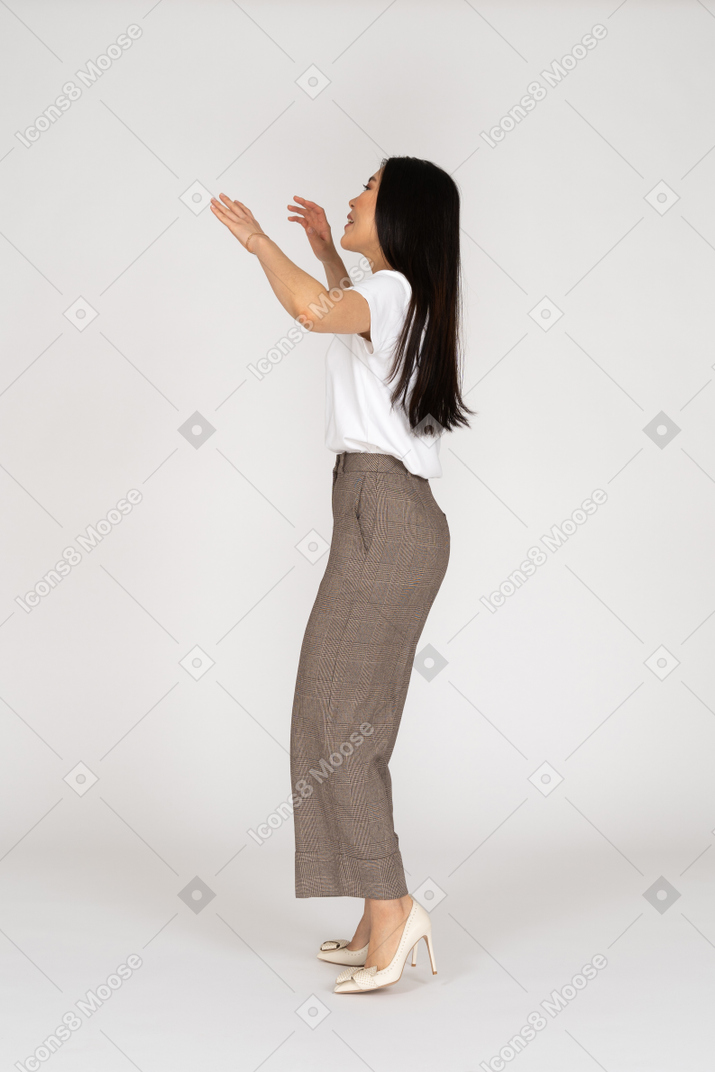 一位年轻的女士，穿着马裤和举起手的t恤的侧视图