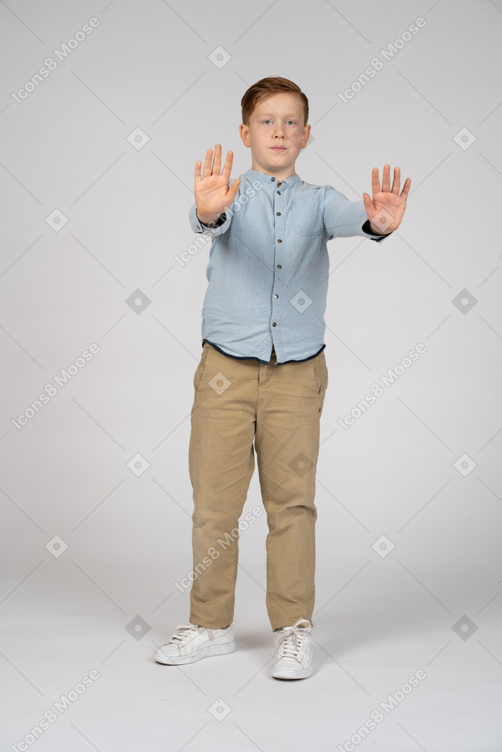 Вид спереди мальчика, стоящего с вытянутыми руками