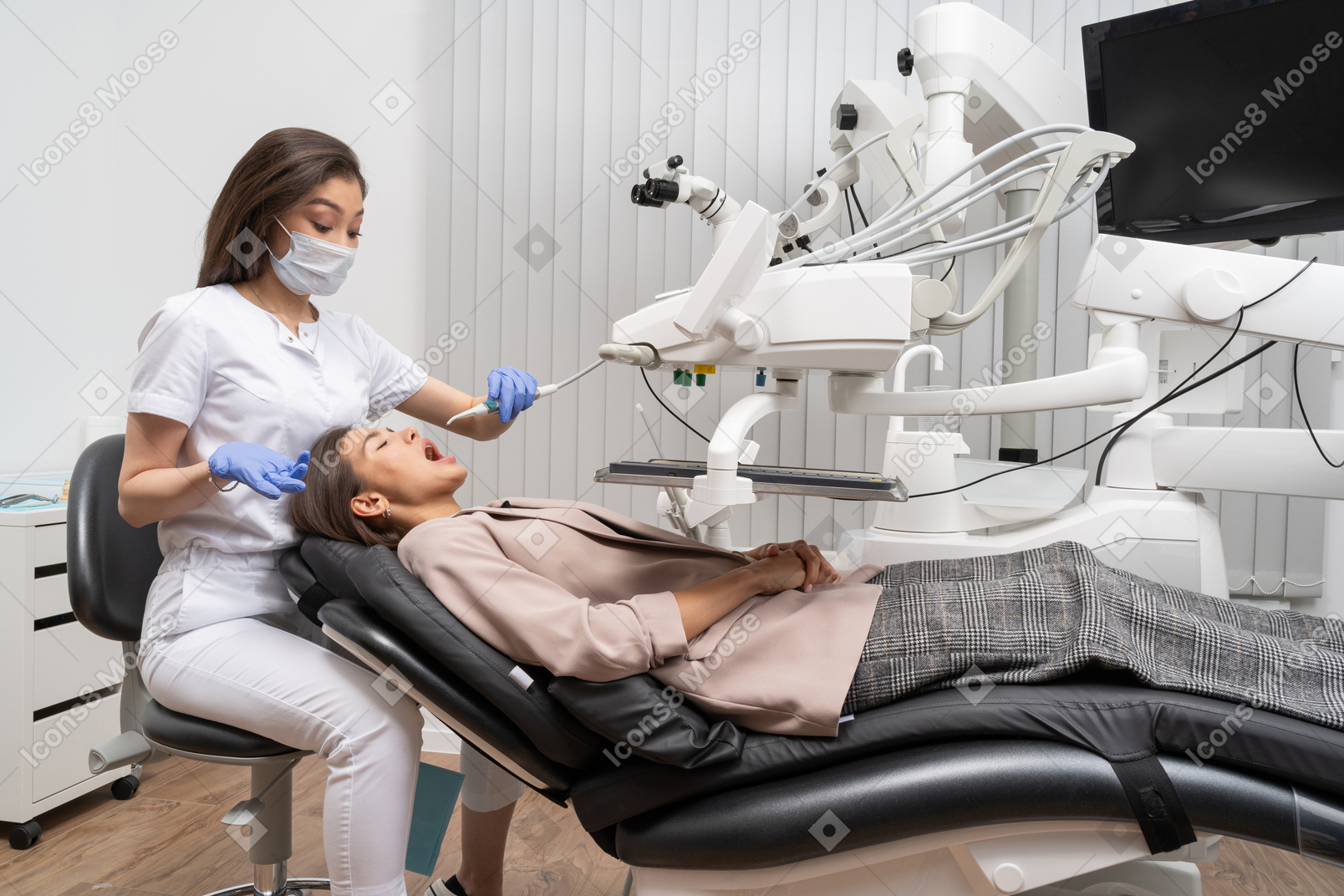 病院のキャビネットに横たわっている女性患者を治療する女性歯科医の全身