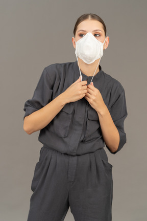 Woman in gray coveralls wearing a respirator