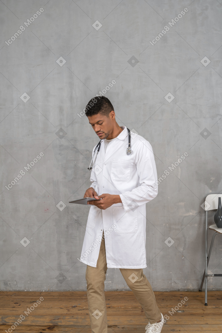 Médico masculino olhando para tablet enquanto caminhava