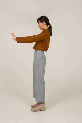 一位身着马裤和衬衫的年轻亚洲女性伸出手臂的侧视图