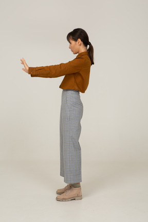 Side view of a young asian female in breeches and blouse outstretching her arm