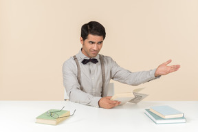 Professor adulto irritado sentado à mesa e ler um livro