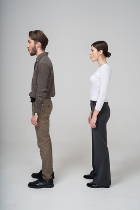 Vista lateral de una joven pareja en ropa de oficina metiendo las mejillas