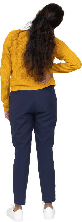 Vista posteriore di una ragazza in abiti casual in posa con la mano sulla schiena