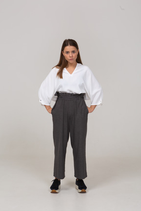 Front view of an offended young lady in office clothing putting hands on hips