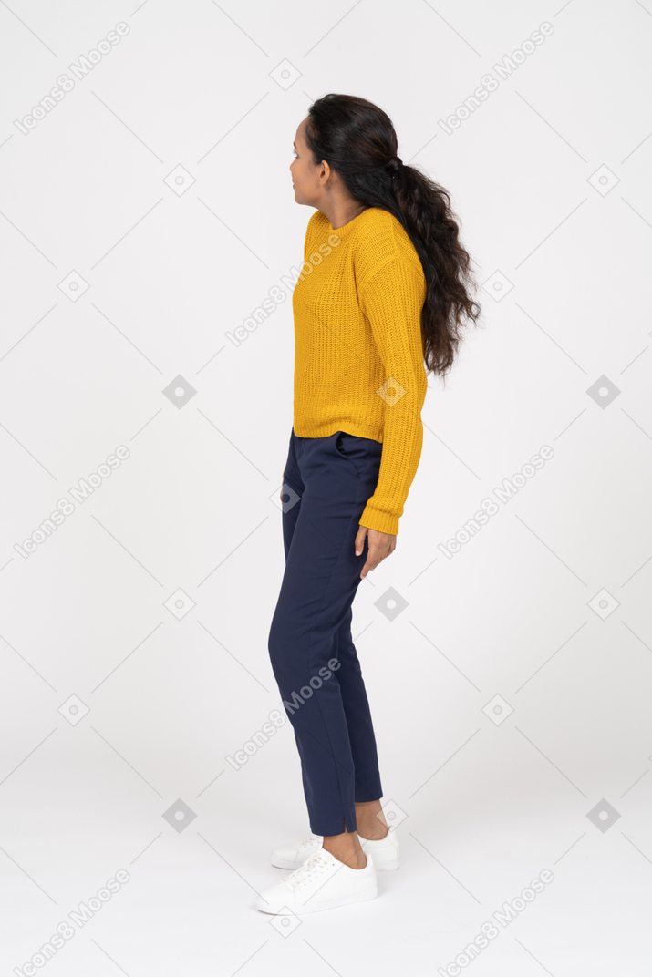 Vista lateral de uma garota com roupas casuais olhando para o lado