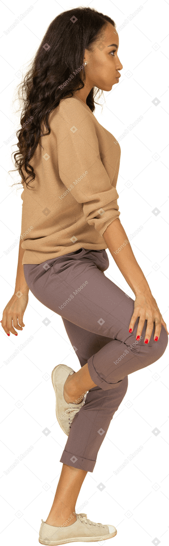 Вид сбоку на темнокожую молодую женщину, касающуюся ее колена