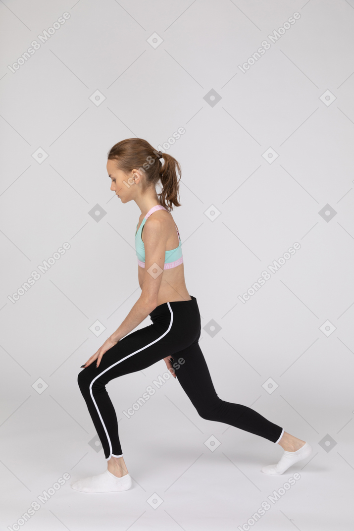 Side view of a teen girl in a sportswear making a lunge