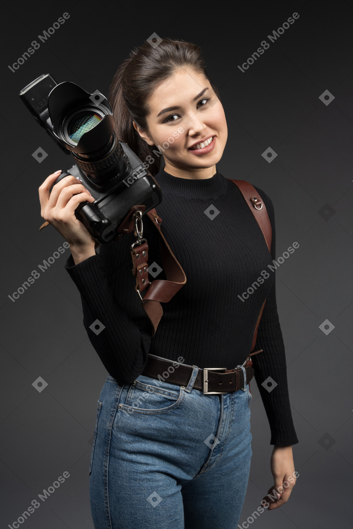 Mulher jovem sorridente em pé com uma câmera