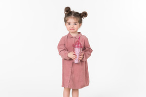 Маленькая девочка держит розовый пластиковый стаканчик