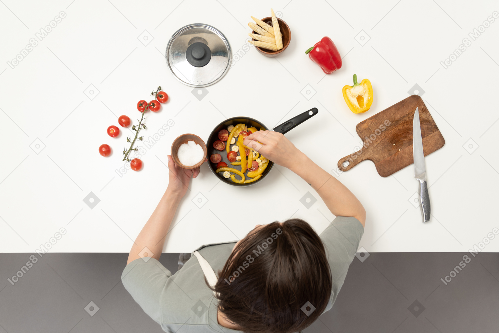 A young woman adding salt to vegetables