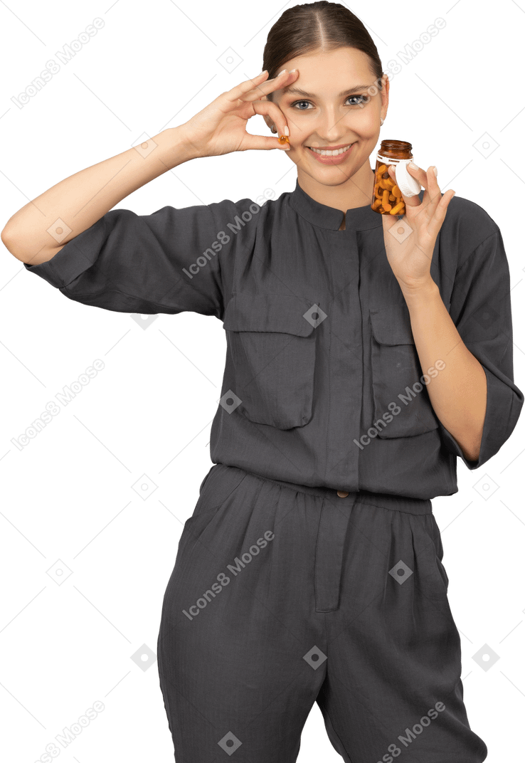 Front view of a young woman in a jumpsuit taking pills out of a jar