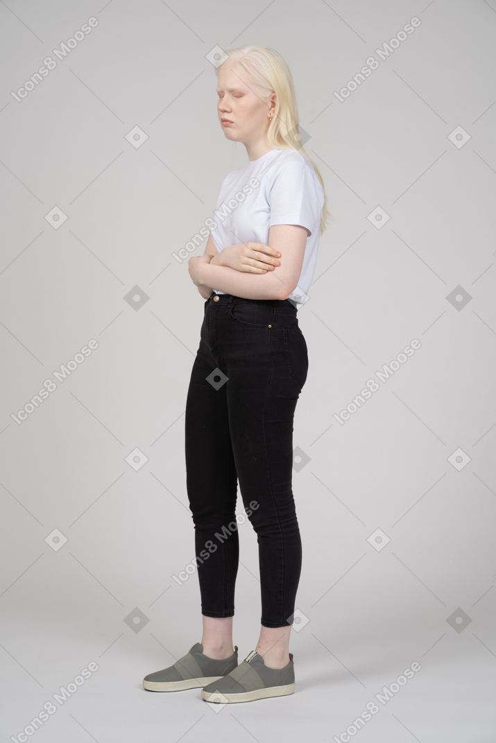 Vista di tre quarti di una giovane donna in abiti casual che incrociano le braccia