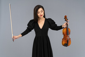 Front view of a female violin player in black dress making a bow