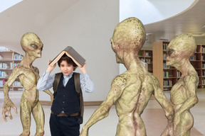 Niño cubriendo su cabeza con un libro y parado alrededor de extraterrestres