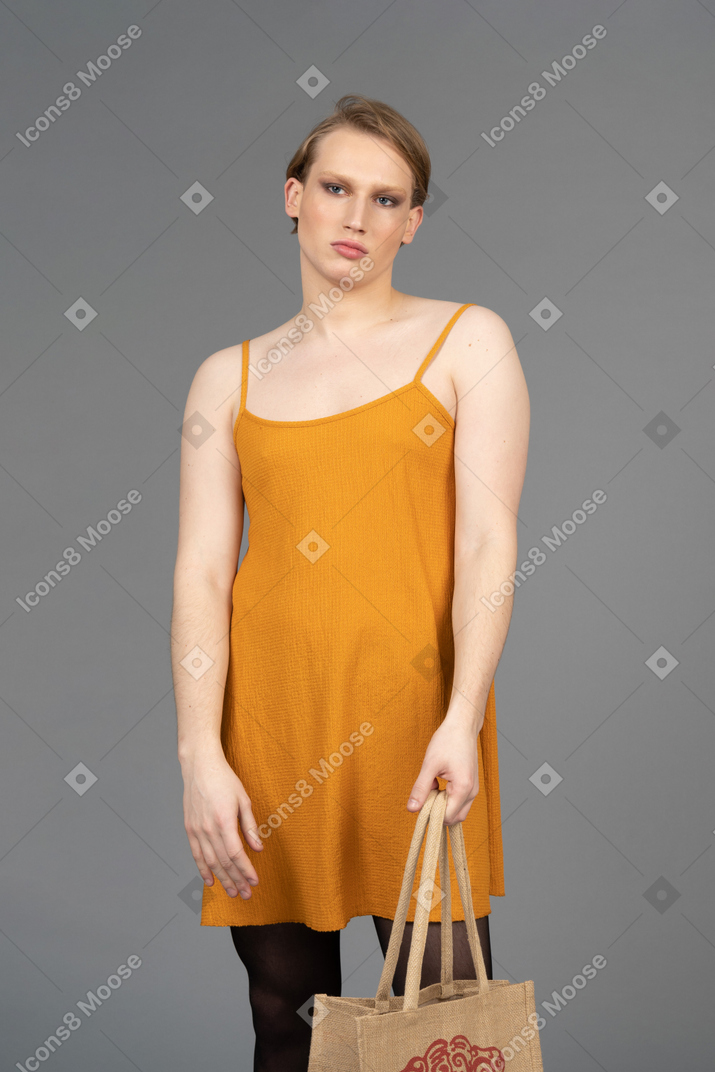 Front view of a young queer person holding a bag