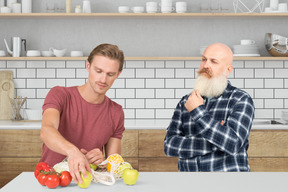 A man taking out vegetables out of bag with man standing next to him