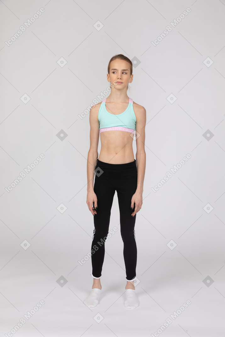 一个年轻的女孩在运动服站着不动，放在一边看的前视图
