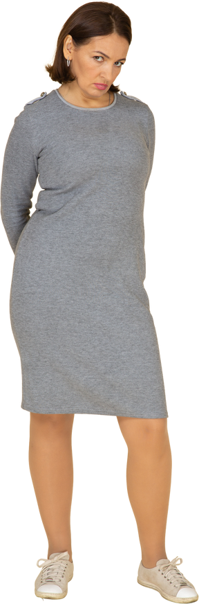 Vista frontal de uma mulher em um vestido cinza em pé com os braços cruzados