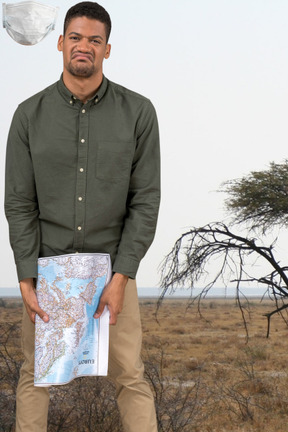 A man standing in a field holding a map