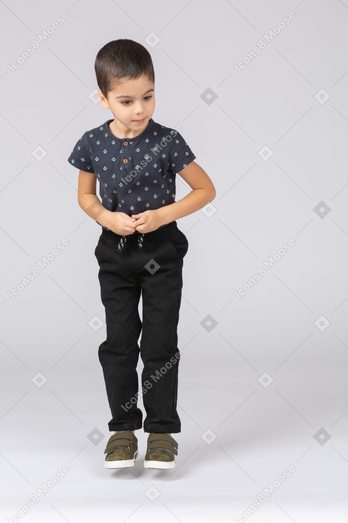 Front view of a cute boy jumping and looking aside
