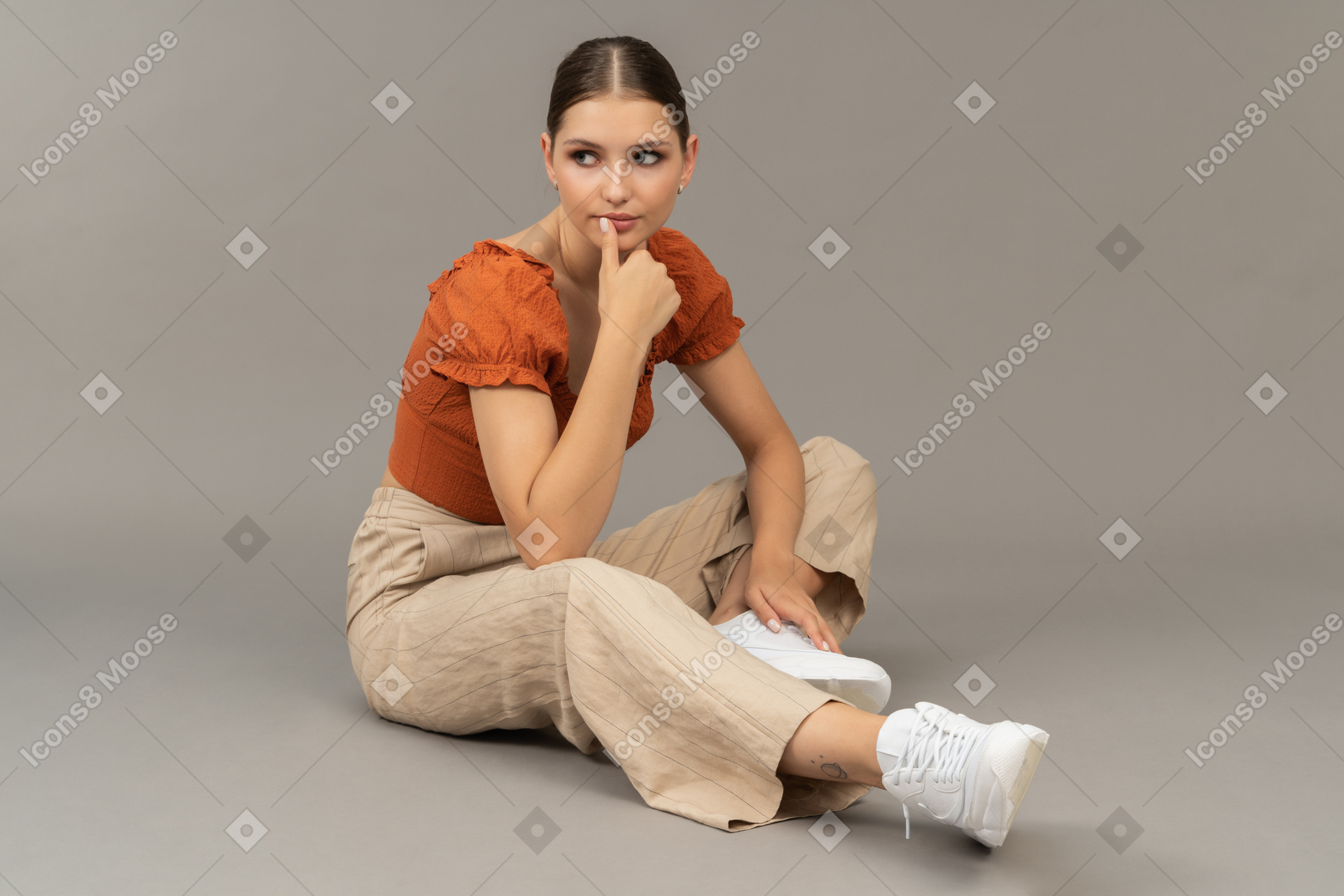 Young woman sits with thumb on her lips